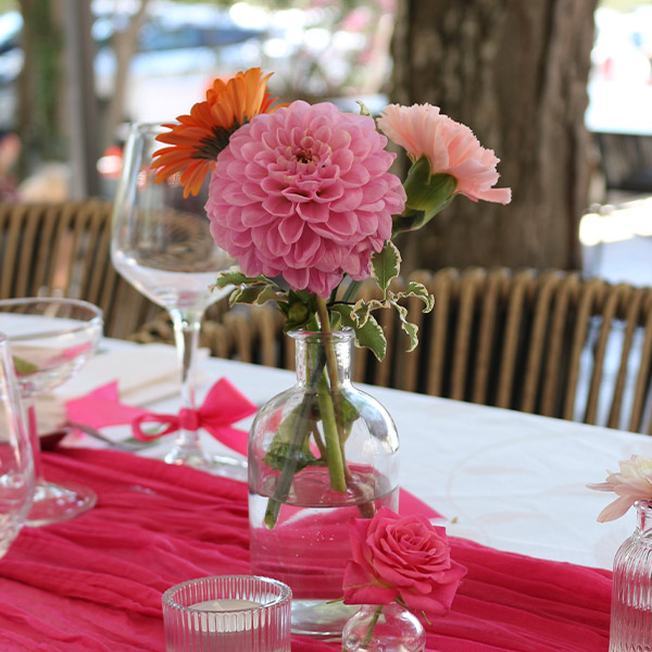 soliflore fleurs roses et orange vase en verre avec chemin de table rose sur une table de mariage